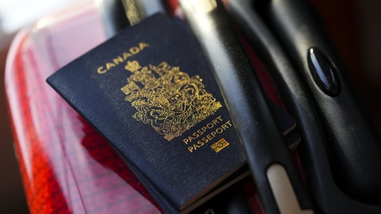 A Canadian passport on a red suitcase.