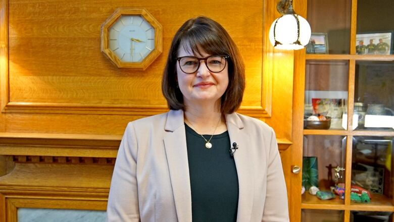 A woman in glasses stands in an office. 