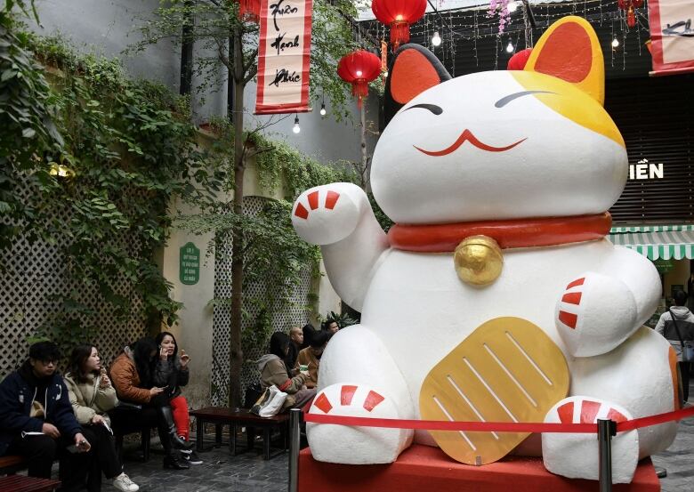 People sit near a giant statue of a cat in Hanoi ahead of Lunar New Year.