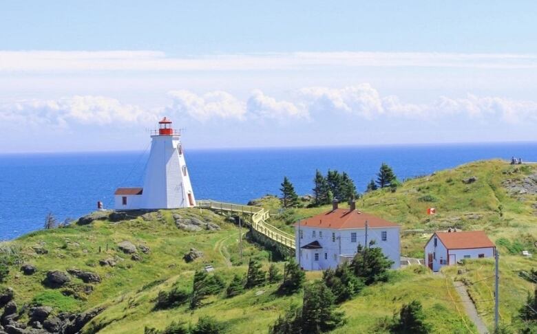 The Swallowtail lighthouse, boathouse and keeper's house featured with the backdrop of the ocean on a sunny day. 