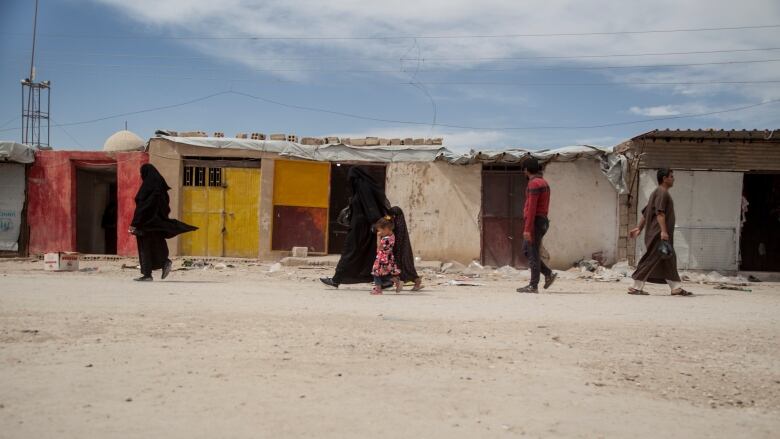 People walk in the marketplace at al-Hol camp that houses some 60,000 refugees, including families and supporters of the Islamic State group.