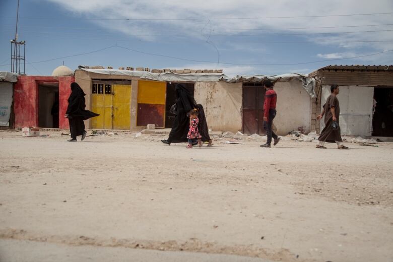 People walk in the marketplace at al-Hol camp that houses some 60,000 refugees, including families and supporters of the Islamic State group.