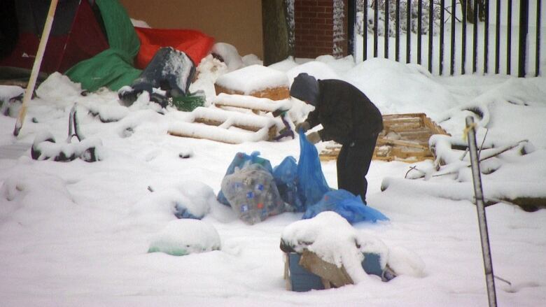 A man sifts through a blue bag at the homeless encampment in Charlottetown.