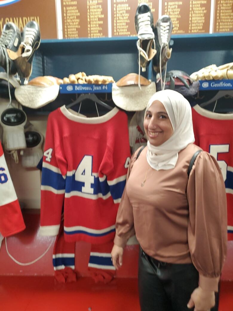 A woman stands beside a hockey jersey.