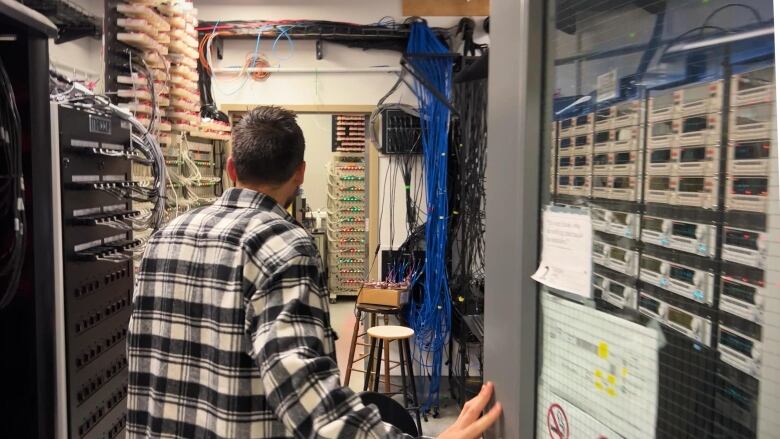 A man in a plaid shirt walks through a room full of battery technology. 