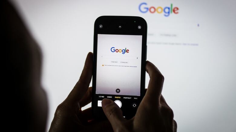 The Google logo on the company's homepage, arranged on an iPhone and a desktop computer in Sydney, Australia, on Friday, Jan. 22, 2021. Google threatened to disable its search engine in Australia if its forced to pay local publishers for news, a dramatic escalation of a months-long standoff with the government. Photographer: David Gray/Bloomberg