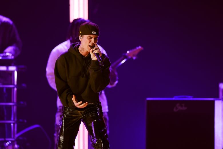 Young pop singer during a concert wearing all black. 