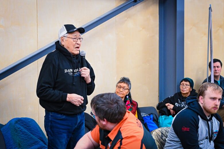 Man in black hoodie at microphone.