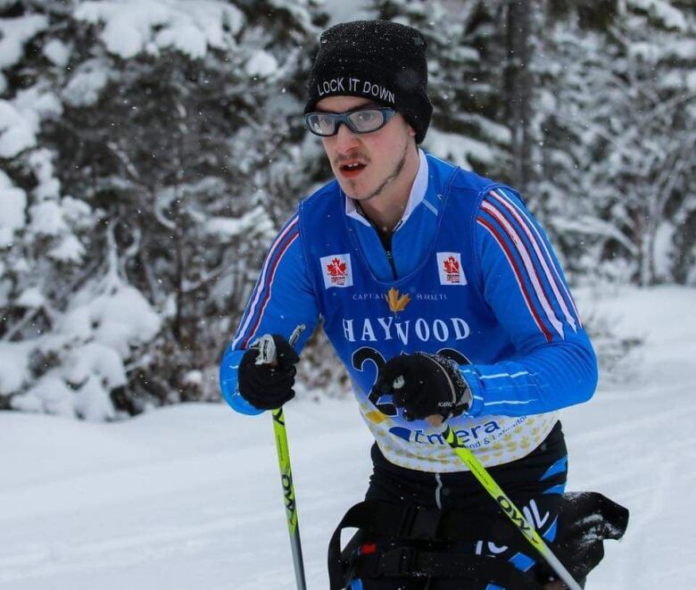 A skier wearing a blue jacket and goggles on a snowy trail. 