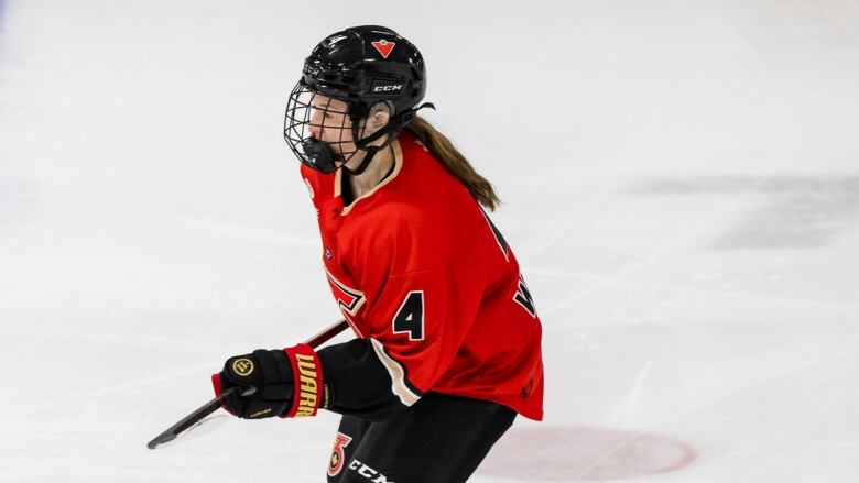 A hockey player in a red jersey skates on open ice.