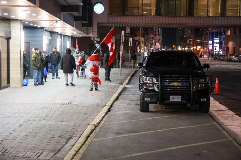 Protesters draped in the Canadian flag are seen outside a Hamilton hotel.