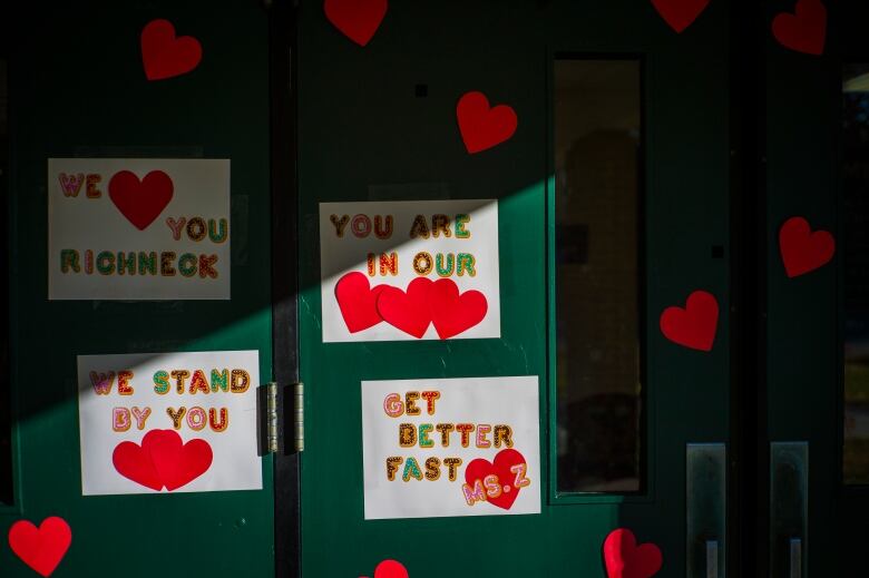 Signs are seen hanging in a window that read Get Better Fast, You Are In Our Hearts, We Stand By You, and We Love You Richneck.