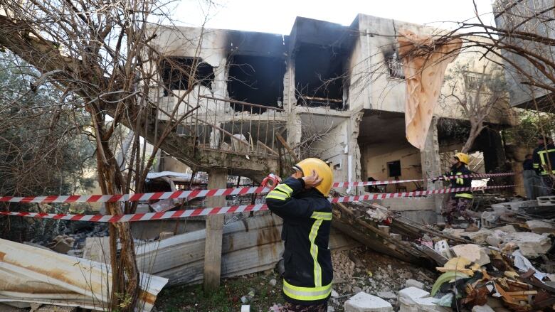 A burned concrete building is shown, with debris outside and a first responder.