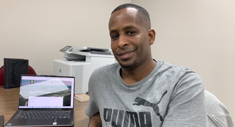 A man poses for a profile photo in an office building. 