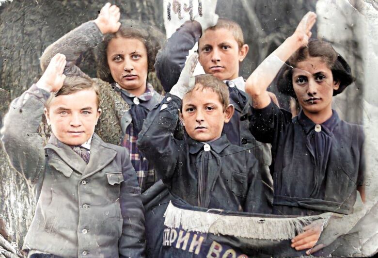 Six children, dressed formally, pose with their right hands to their foreheads in a type of salute.