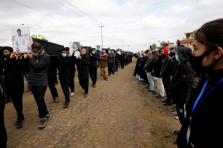 Mourners carry remains of Yazidi victims of ISIS following their exhumation from a mass grave near Kojo, Iraq, February 6, 2021.