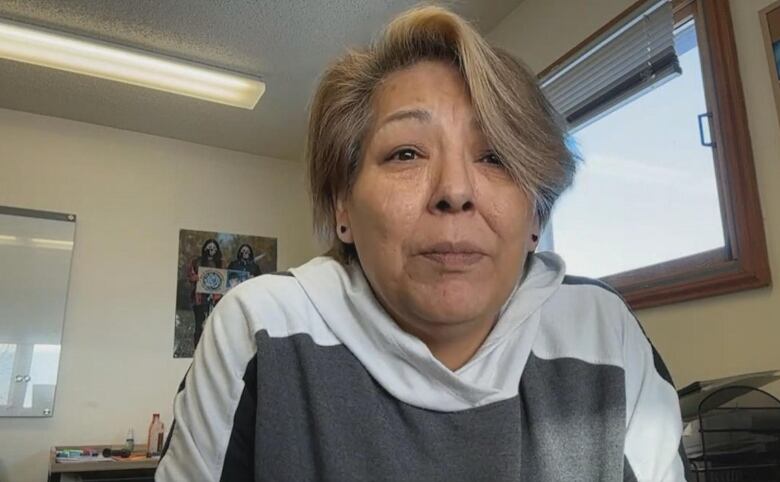 A woman sits in an office building looking at the camera