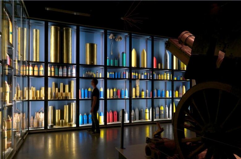 A man perusing a museum display of various kinds of WWI artillery shells.