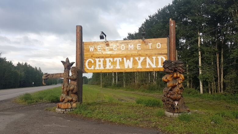 A wooden sign and carvings reading 'Welcome to Chetwynd.'