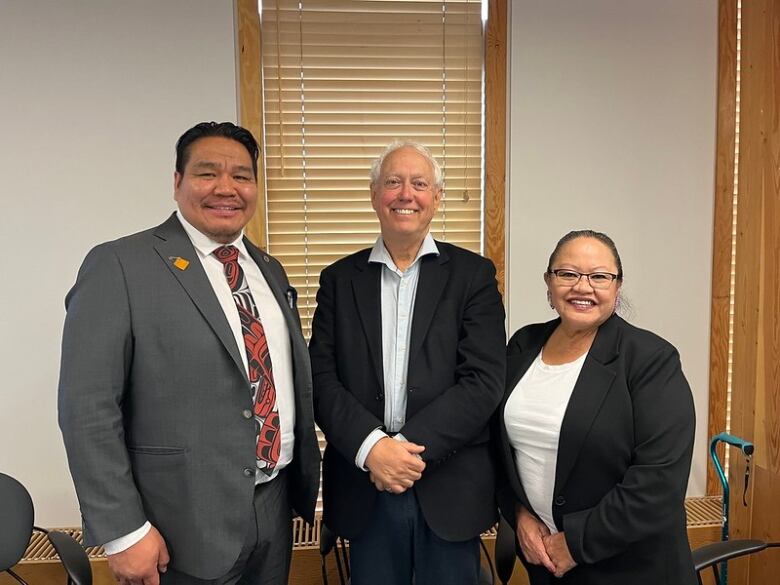 An older man representing the province of B.C. is flanked by two leaders of an Indigenous community and all three of them are smiling.