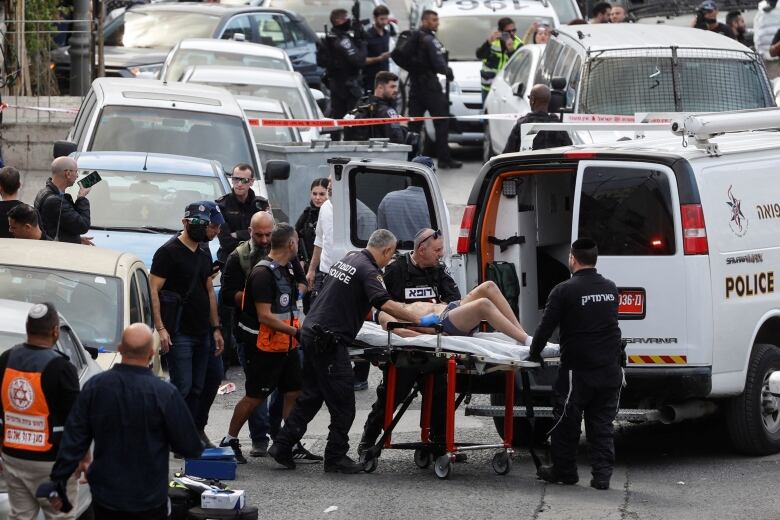 Paramedics wheel a person on a stretcher.