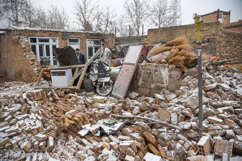 A man stands behind earthquake rubble.