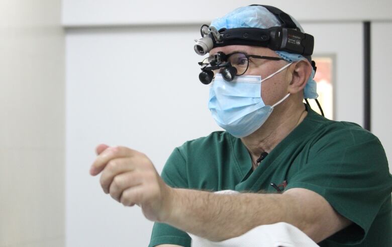 A doctor wears a surgical outfit and equipment before scrubbing up for an operation.