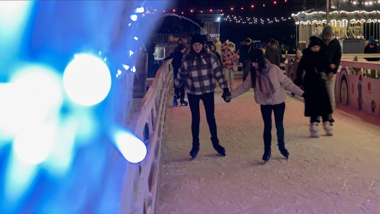 Two skaters hold hands at an outdoor rink in the capital Kyiv,  even as Russian missiles bombard the city.