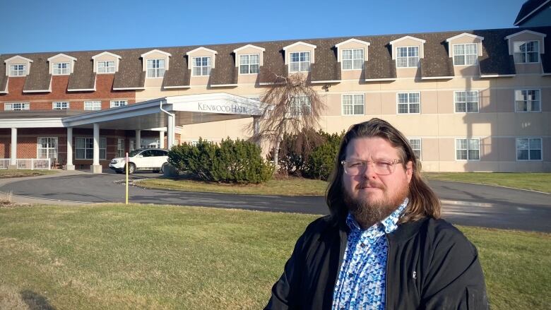 A man stands in front of a long-term care home.