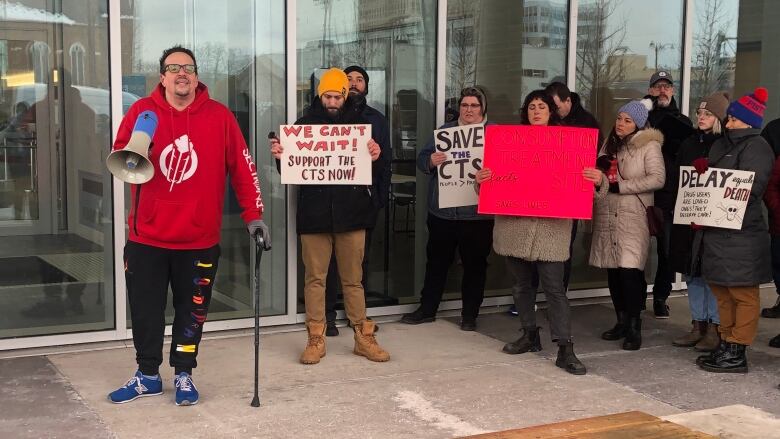 protestors holding signs, one is holding a megaphone