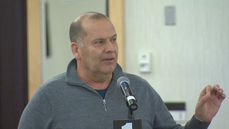 Chris Collins stands at a microphone at a public meeting.