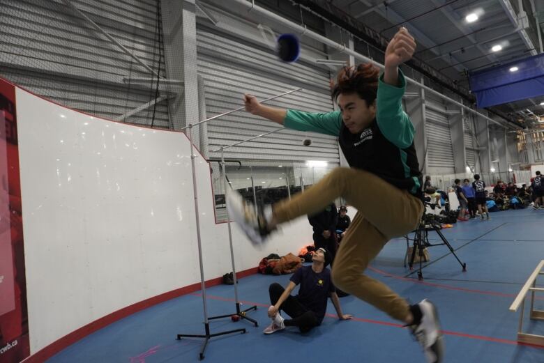 A young man jumps trying to kick an object. 