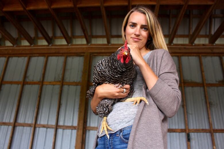 A lady holding a chicken stands on the centre-right of the photo, facing the camera.