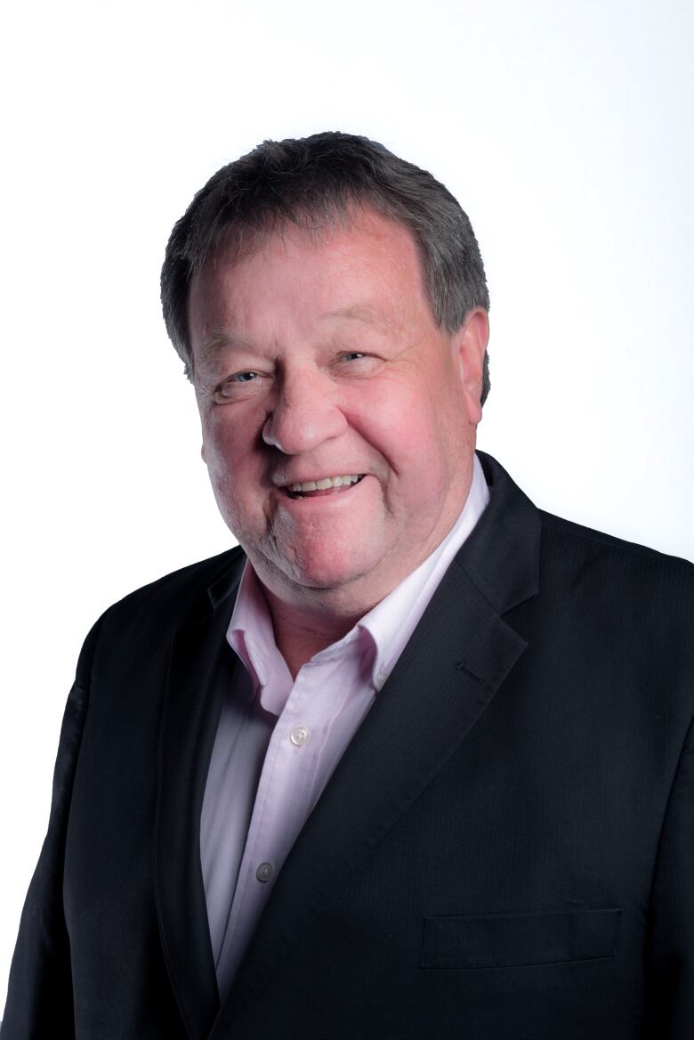 A headshot of a man wearing a suit and smiling. 