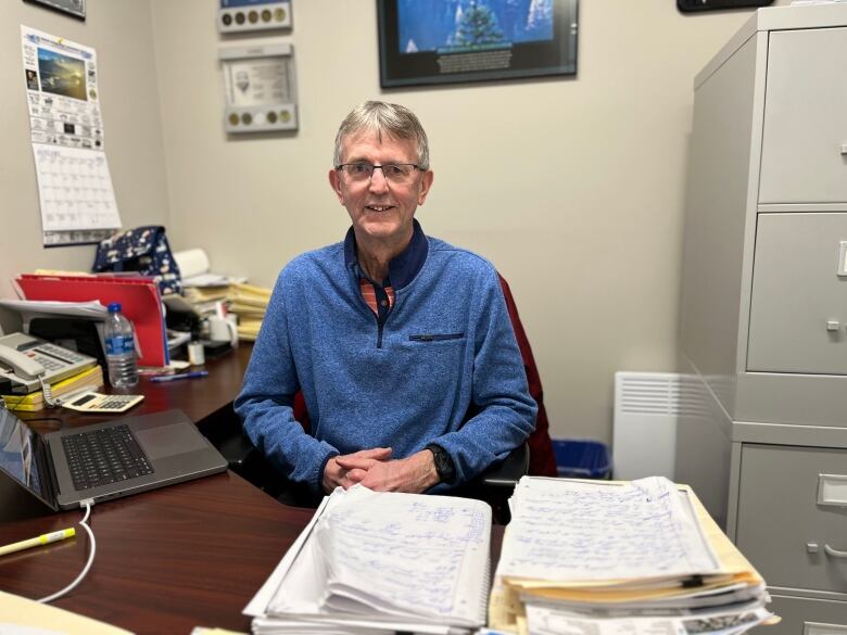 A man sitting in an office surrounded by papers. 