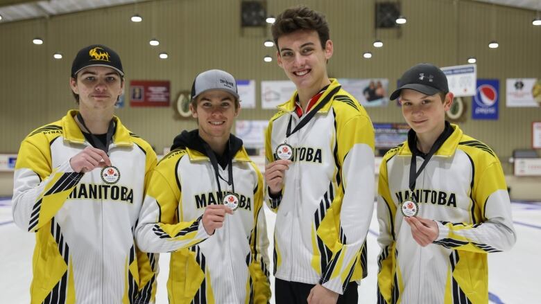 Four teenage boys with Manitoba curling jacket, hold up medals.