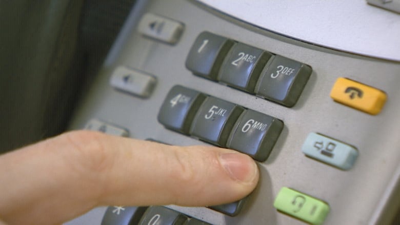 Finger pressing the number 9 on a landline telephone.