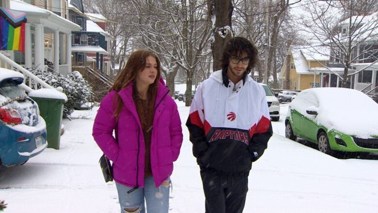 Two young adults walk in the snow. 