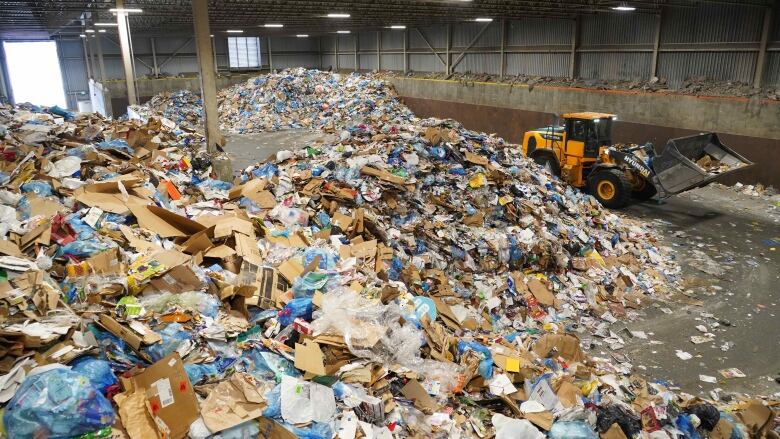 Large piles of recyclable material in warehouse with bucket loader