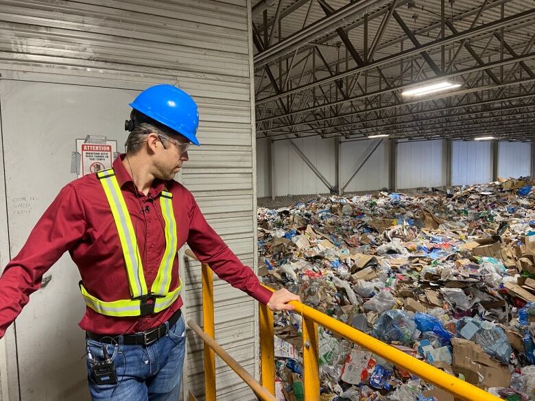 Man looking down from balcony onto piles of recycling