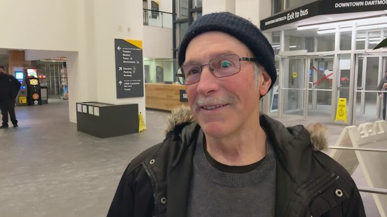 A man with glasses and a navy toque stands in the entrance lobby of Alderney Landing in Dartmouth