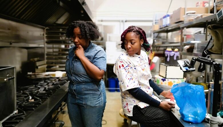 Rochelle Williams looks over Aliyah Fraser's shoulder in the kitchen.