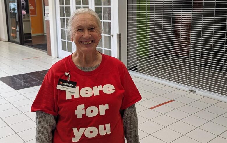 Charlene Bowman stands in front of a store wearing a red shirt that says 