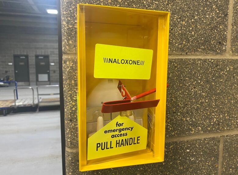 A yellow box holds emergency naloxone. A red handle can be pulled to access the naloxone.