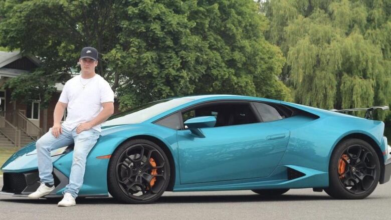 Man sits on a Lamborghini luxury car.