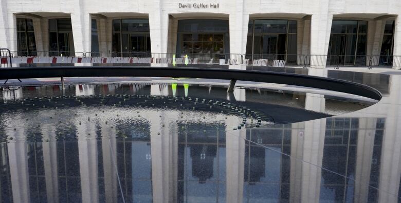 The outside of a concert hall, with a pool of water out front.