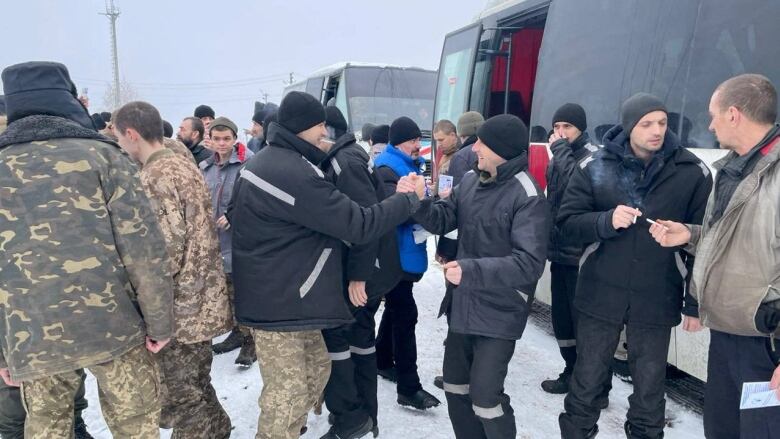 Men greet each other in front of buses.