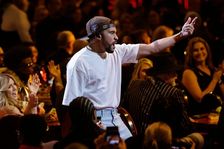 A man in a white t-shirt sings amid a crowd. 