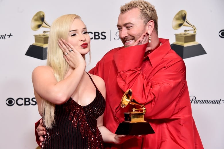 Two people pose with grammy award