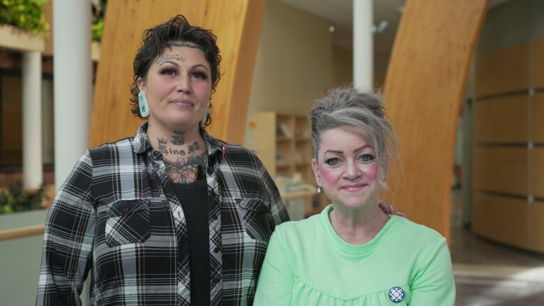 Two women stand together in a campus building.